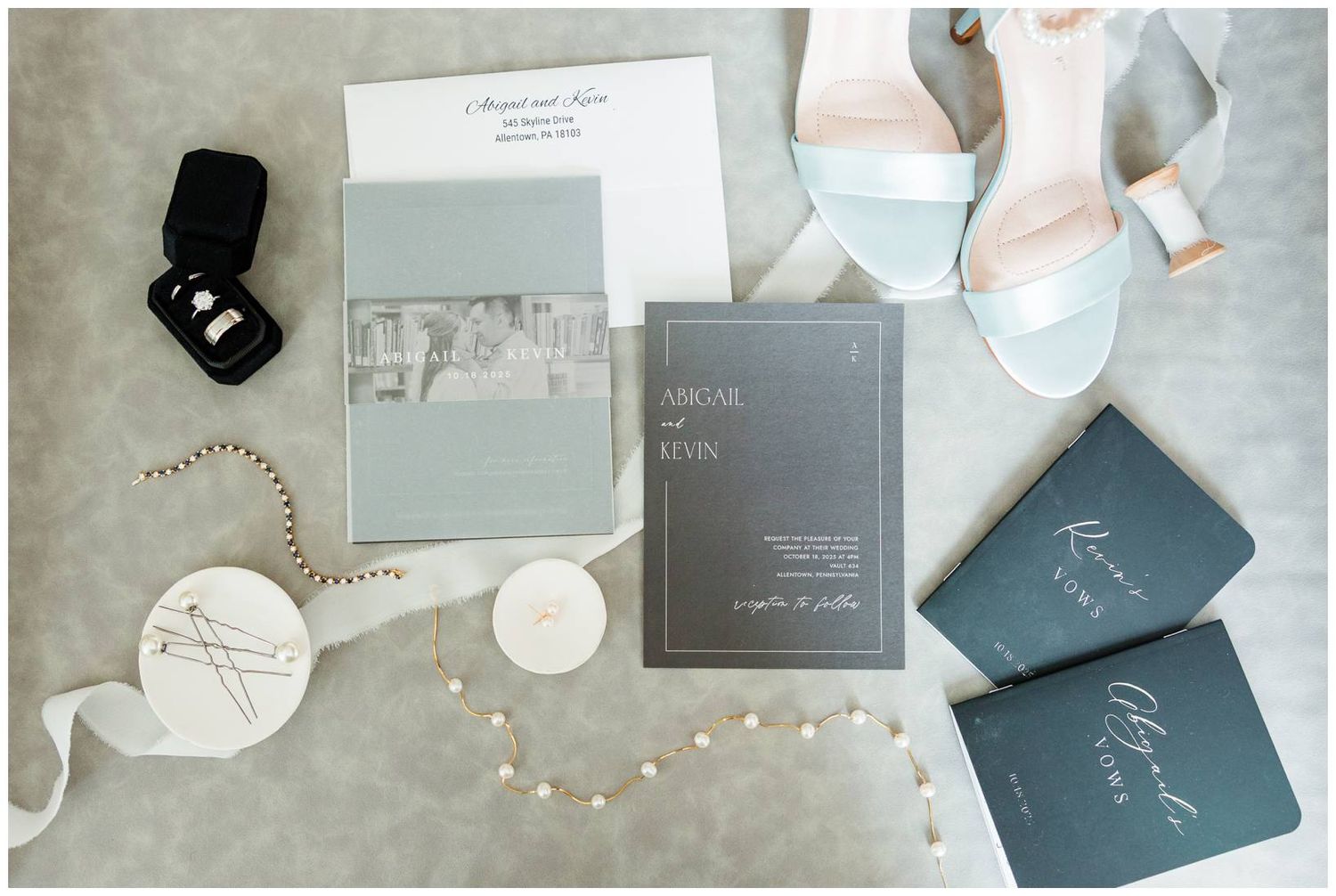 Elegant wedding invitations and stationery in gray and white with modern calligraphy laid out on a light surface.
