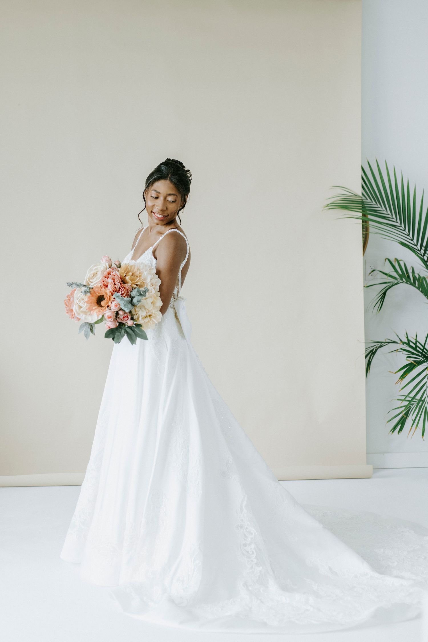 Elegant bridal portrait series showing a flowing white wedding gown with train against a minimal backdrop with palm leaves.