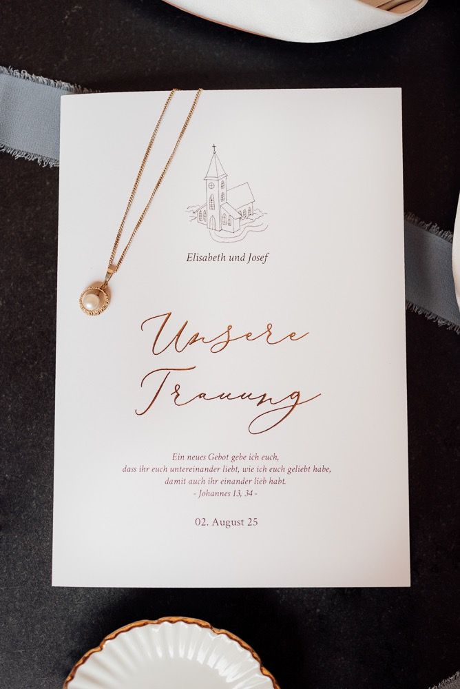 Elegant wedding invitation cards in white with copper calligraphy text and delicate design elements.
