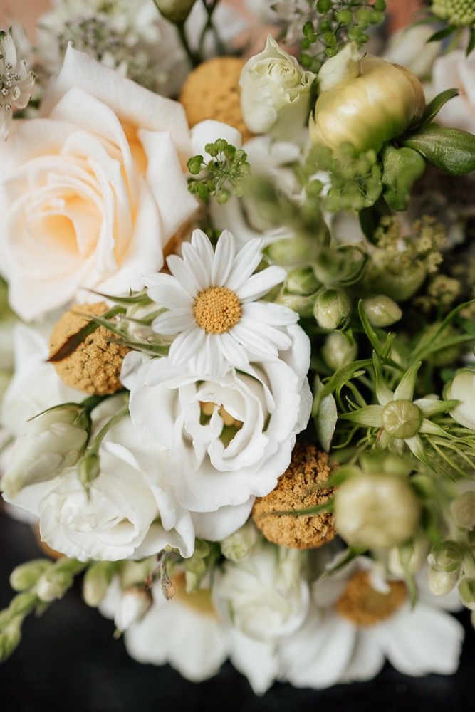 Elegant white floral wedding bouquet with daisies, roses and delicate greenery arranged in a romantic style.