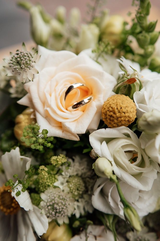 Close-up of delicate peach and white roses with greenery in an elegant wedding bouquet arrangement.