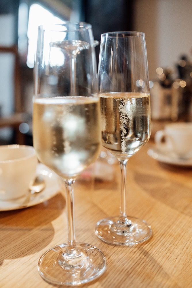 Empty wine glasses sit on a wooden table in a restaurant setting with soft focus lighting.
