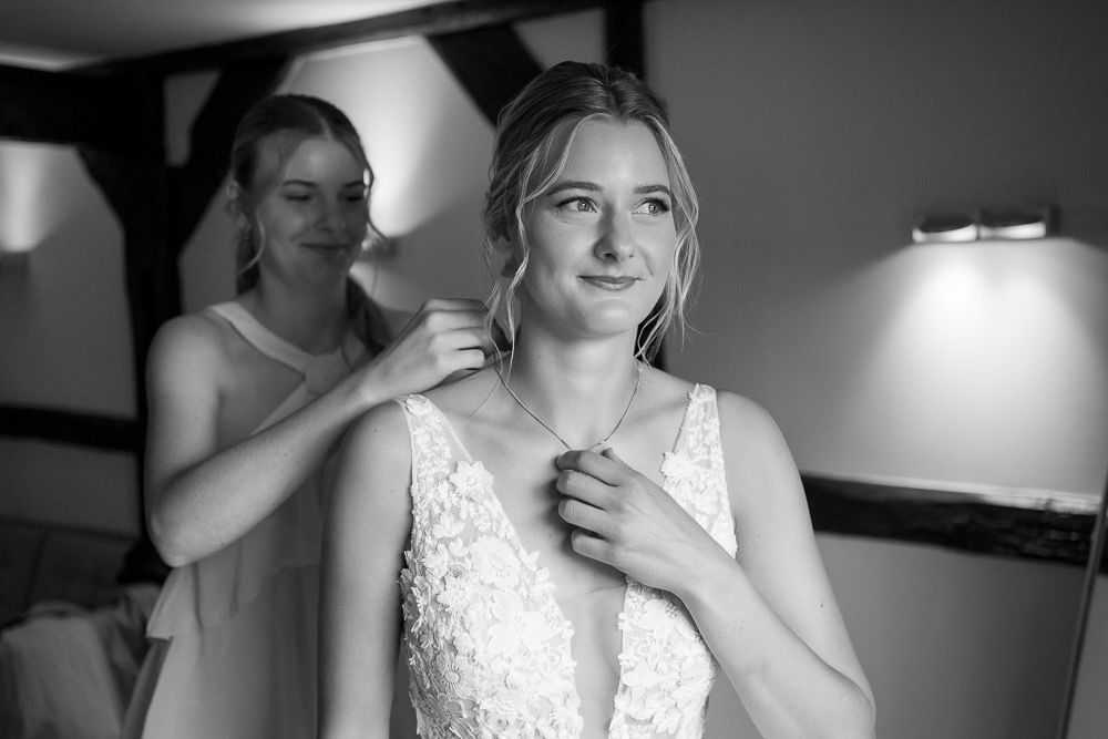 Black and white portrait of someone in an elegant lace wedding dress during preparation.