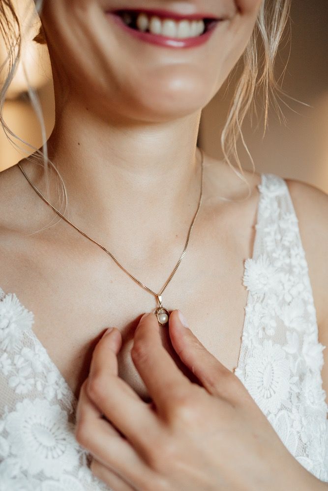 Close-up detail of bridal jewelry and lace dress neckline.