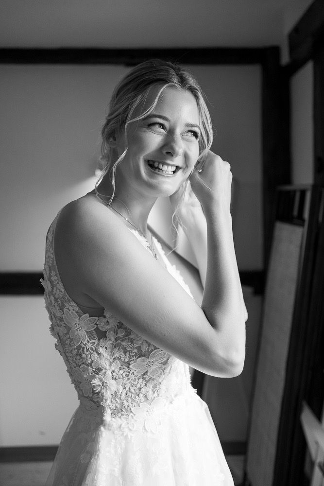 Candid black and white photo of someone in a lace wedding gown laughing joyfully.