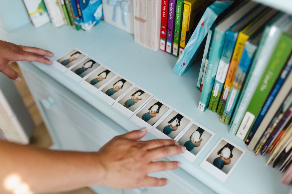 Hand reaching for a book on a shelf filled with colorful books in a library or bookstore.