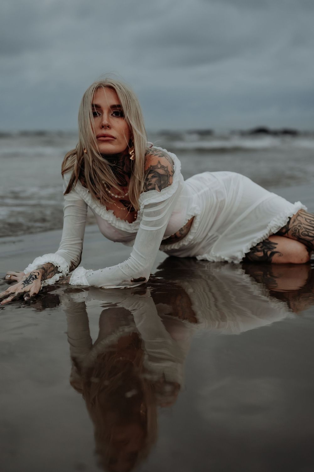 Artistic portrait of person lying in shallow water wearing white dress at gladstone beach.