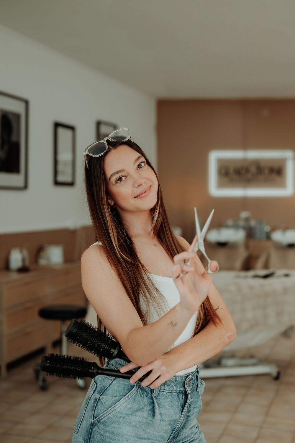 Casual pose with hairstyling tools in a modern salon environment.