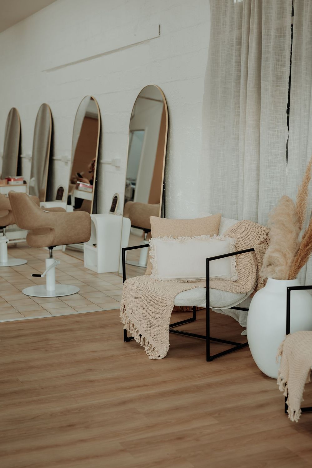 Modern salon interior with white chairs, mirrors, and beige accents creating a minimalist aesthetic.