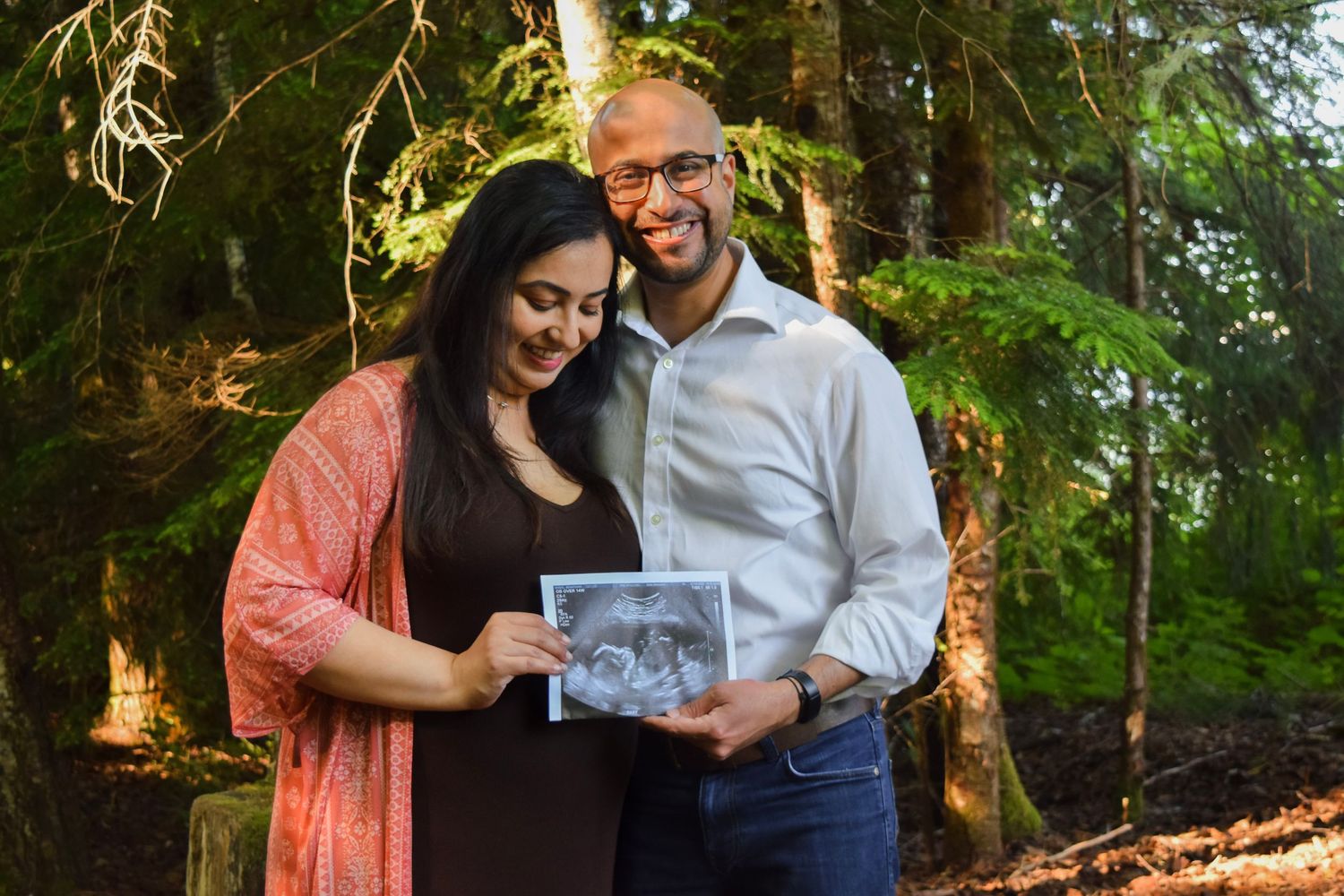 Couple sharing intimate moment in sunlit forest setting.