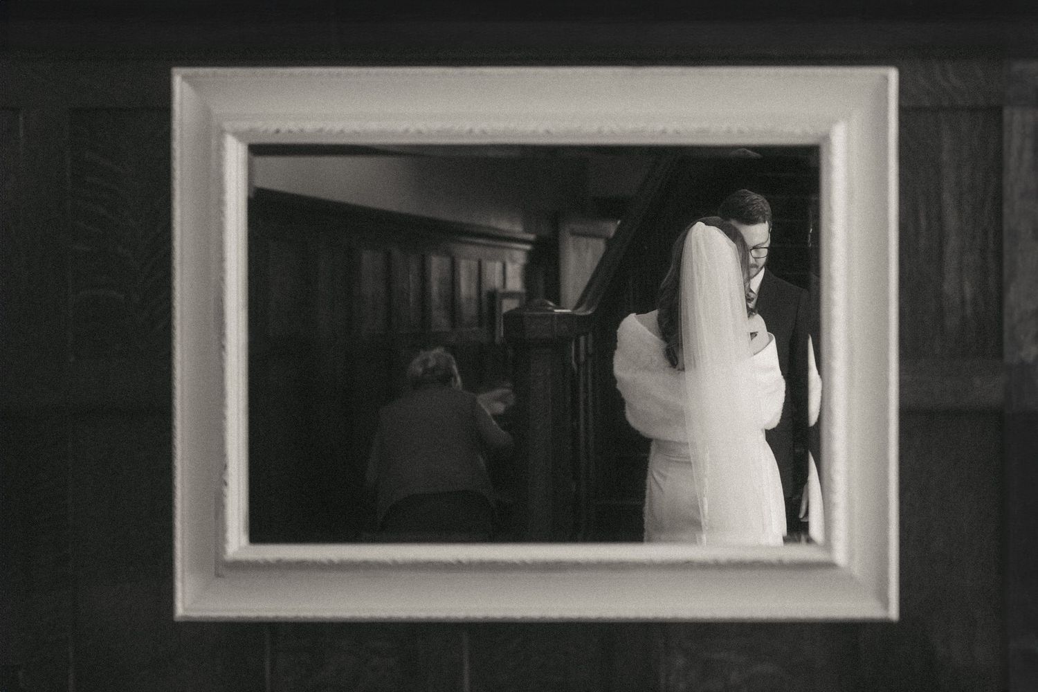 Black and white photograph of a modern art gallery interior with white framed artworks displayed on dark walls.