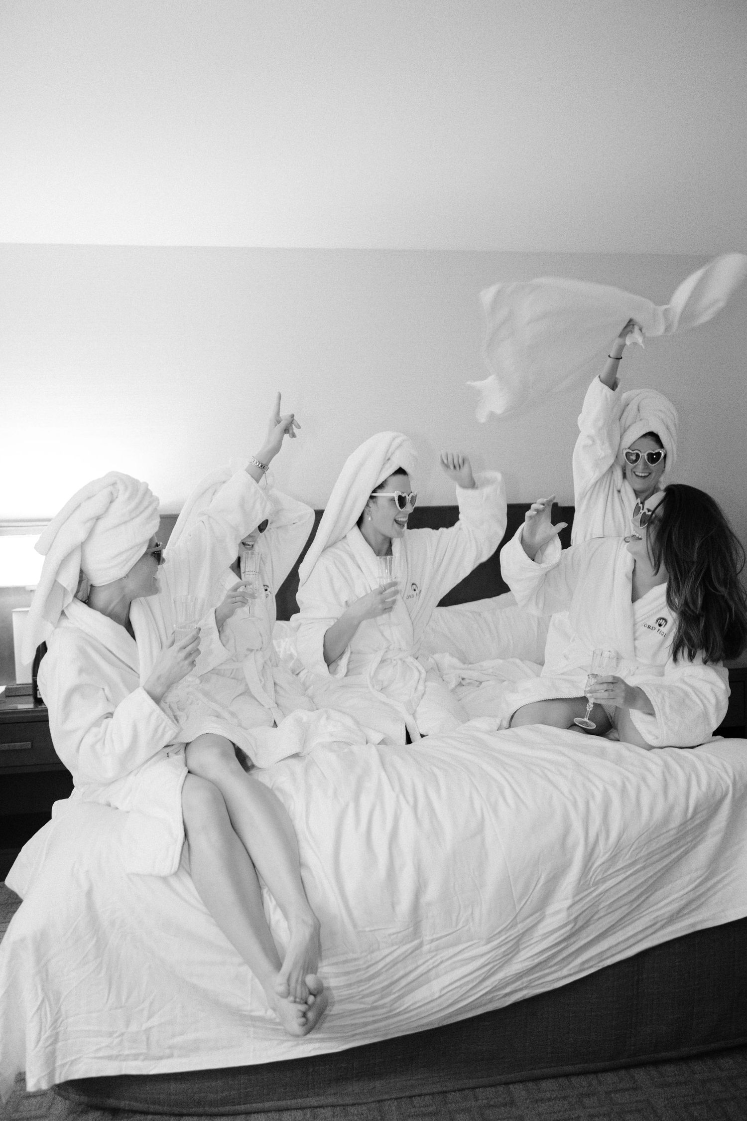 A series of black and white photos showing someone in white clothing lying on a bed in different relaxed poses.