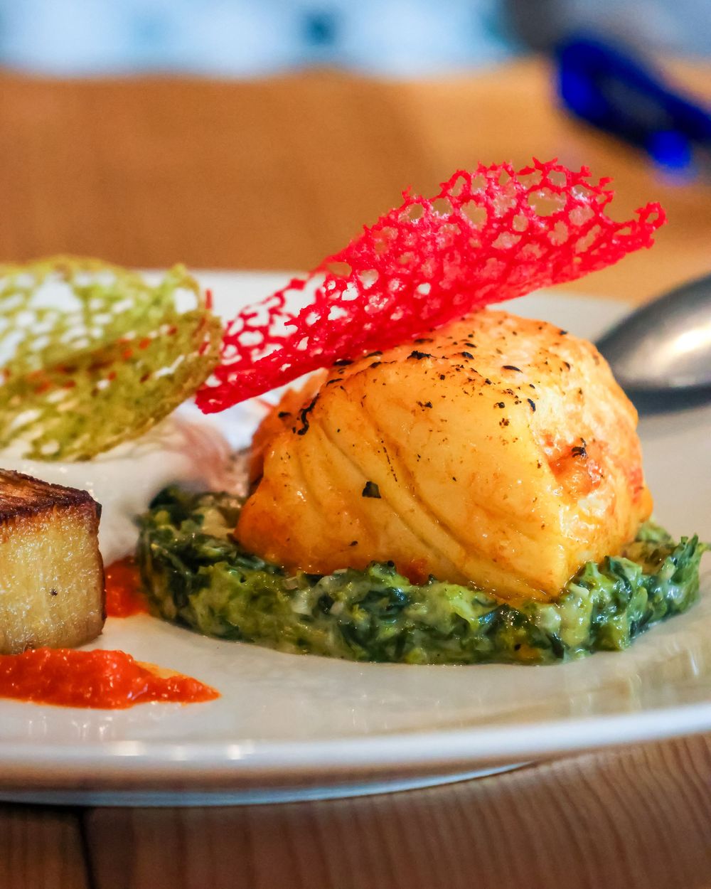 Gourmet salmon dish plated with colorful sauces and garnishes.