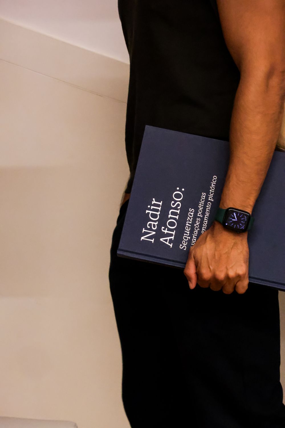 Close-up of hands holding dark blue books or documents.