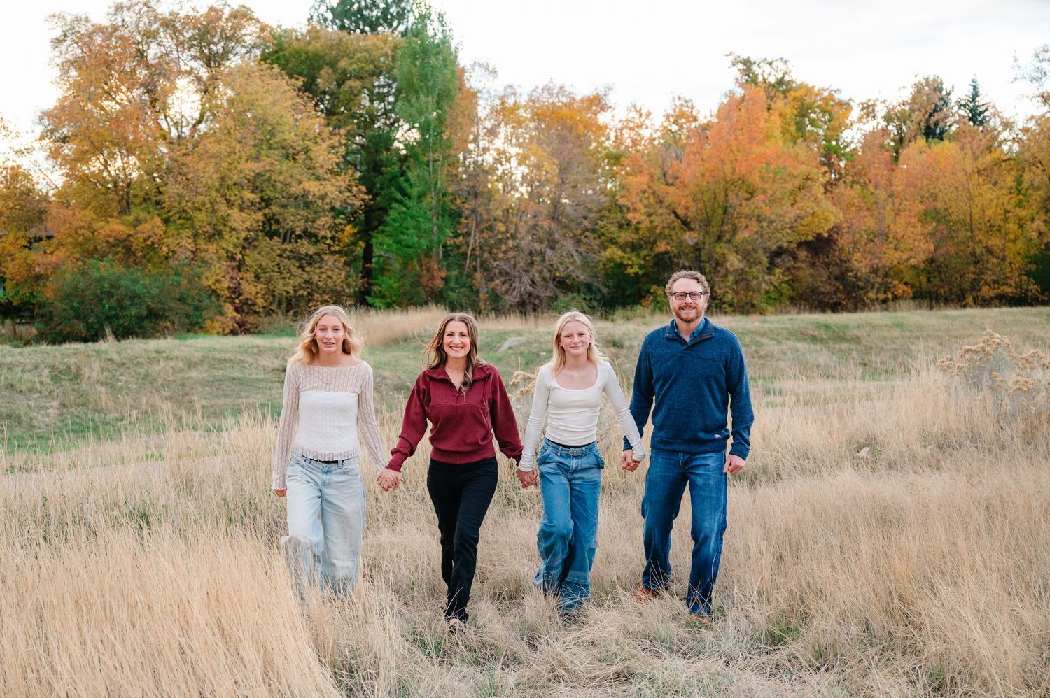 A group of people walk together through a golden autumn field during sunset.