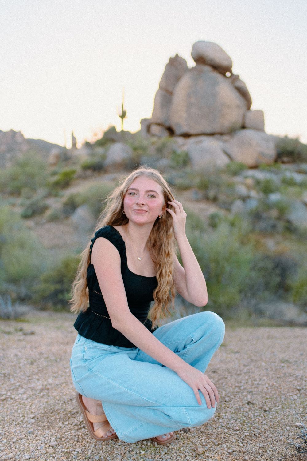 Image of a high school senior taking her senior photos  on large boulders at the McDowell Sonoran Preserve in Scottsdale, Arizona.