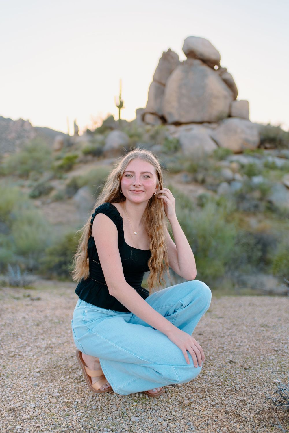 Image of a high school senior taking her senior photos  on large boulders at the McDowell Sonoran Preserve in Scottsdale, Arizona.