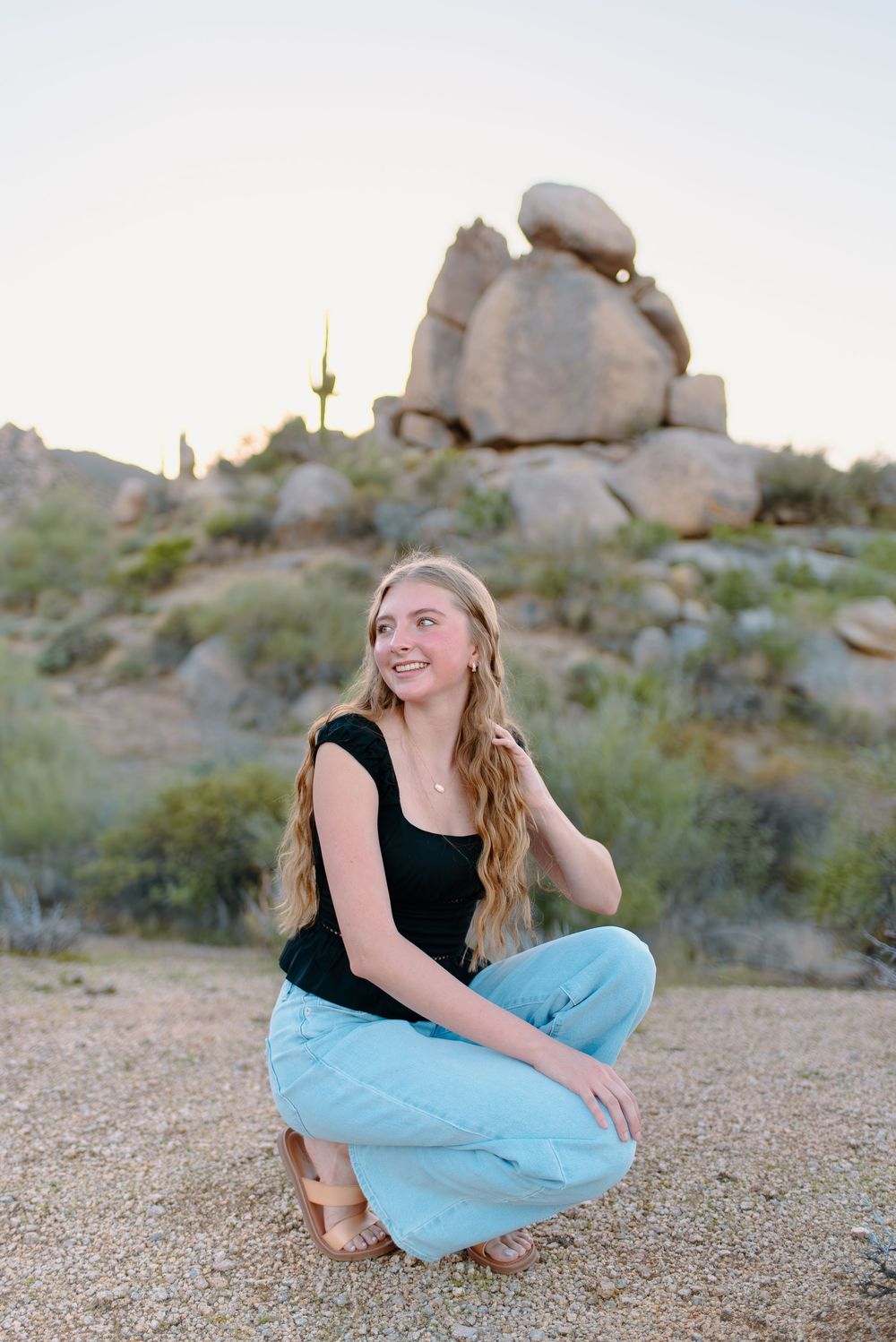 Image of a high school senior taking her senior photos  on large boulders at the McDowell Sonoran Preserve in Scottsdale, Arizona.