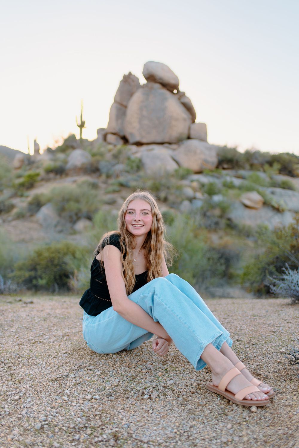 Image of a high school senior taking her senior photos  on large boulders at the McDowell Sonoran Preserve in Scottsdale, Arizona.