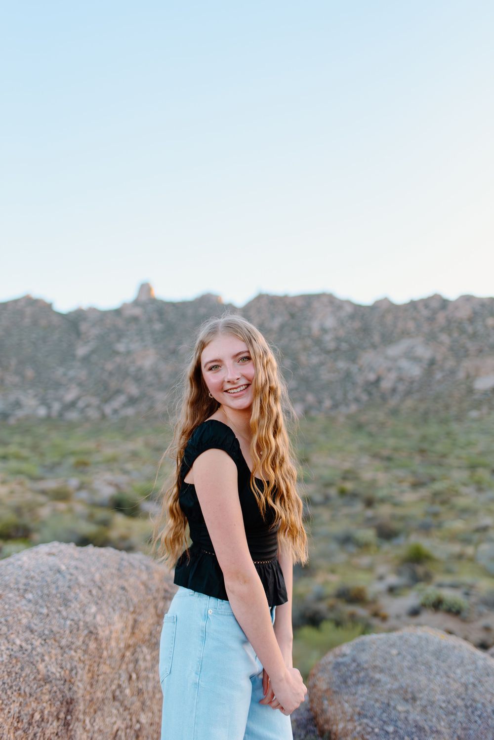 Image of a high school senior taking her senior photos  on large boulders at the McDowell Sonoran Preserve in Scottsdale, Arizona.