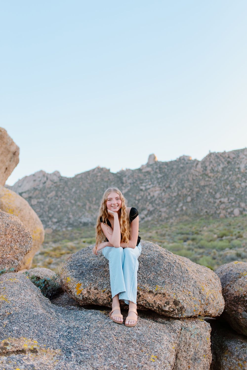 Image of a high school senior taking her senior photos  on large boulders at the McDowell Sonoran Preserve in Scottsdale, Arizona.