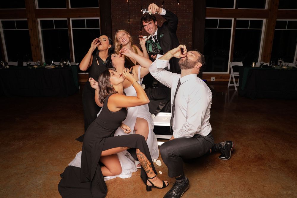 A group of dancers perform energetic bachata dance moves on a dark wooden dance floor at a social event.