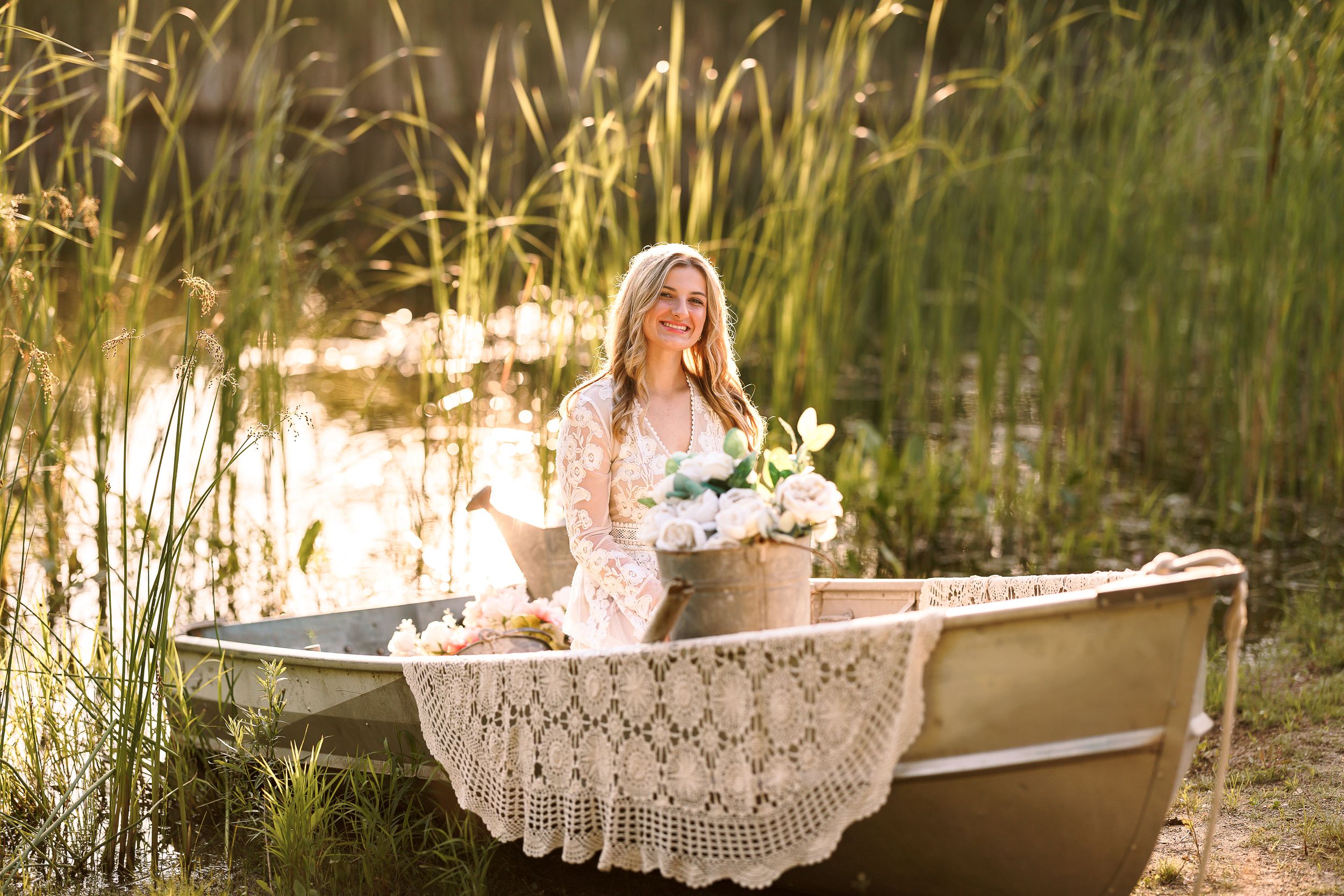 Romantic scene with lace-draped boat on lake at sunset with flowers.