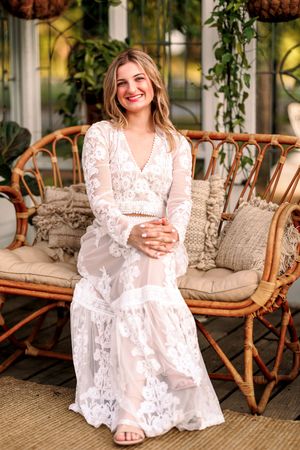 White lace dress on wicker furniture in sunlit conservatory setting.