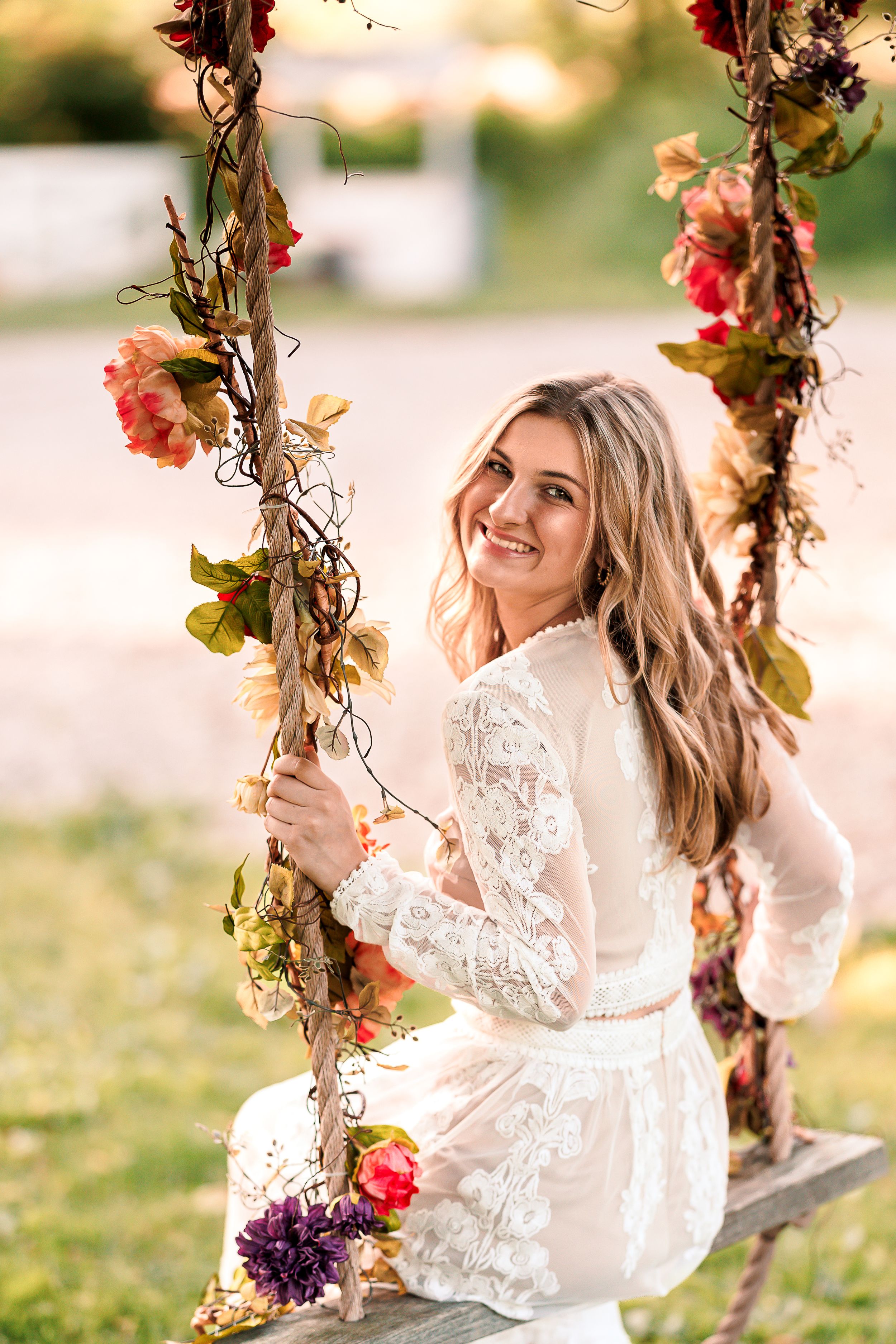 Ethereal portrait on floral swing with romantic garden backdrop.