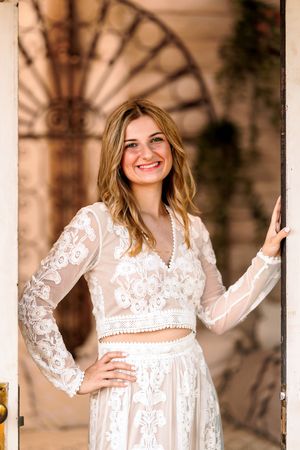 Elegant two-piece lace outfit against architectural backdrop with decorative details.