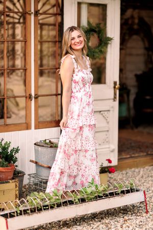 Pink floral maxi dress portrait in rustic garden setting.
