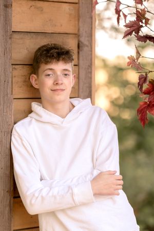 Portrait series against wooden wall backdrop in warm autumn lighting with white hoodie.