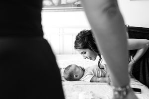 Intimate black and white moment between parent and baby on floor.