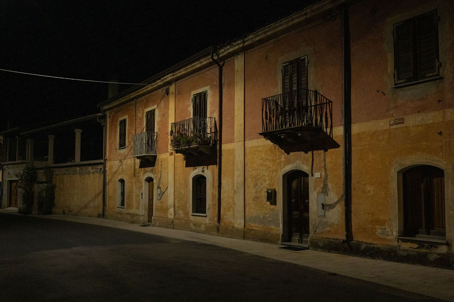 Row of old Italian buildings with balconies illuminated at night.