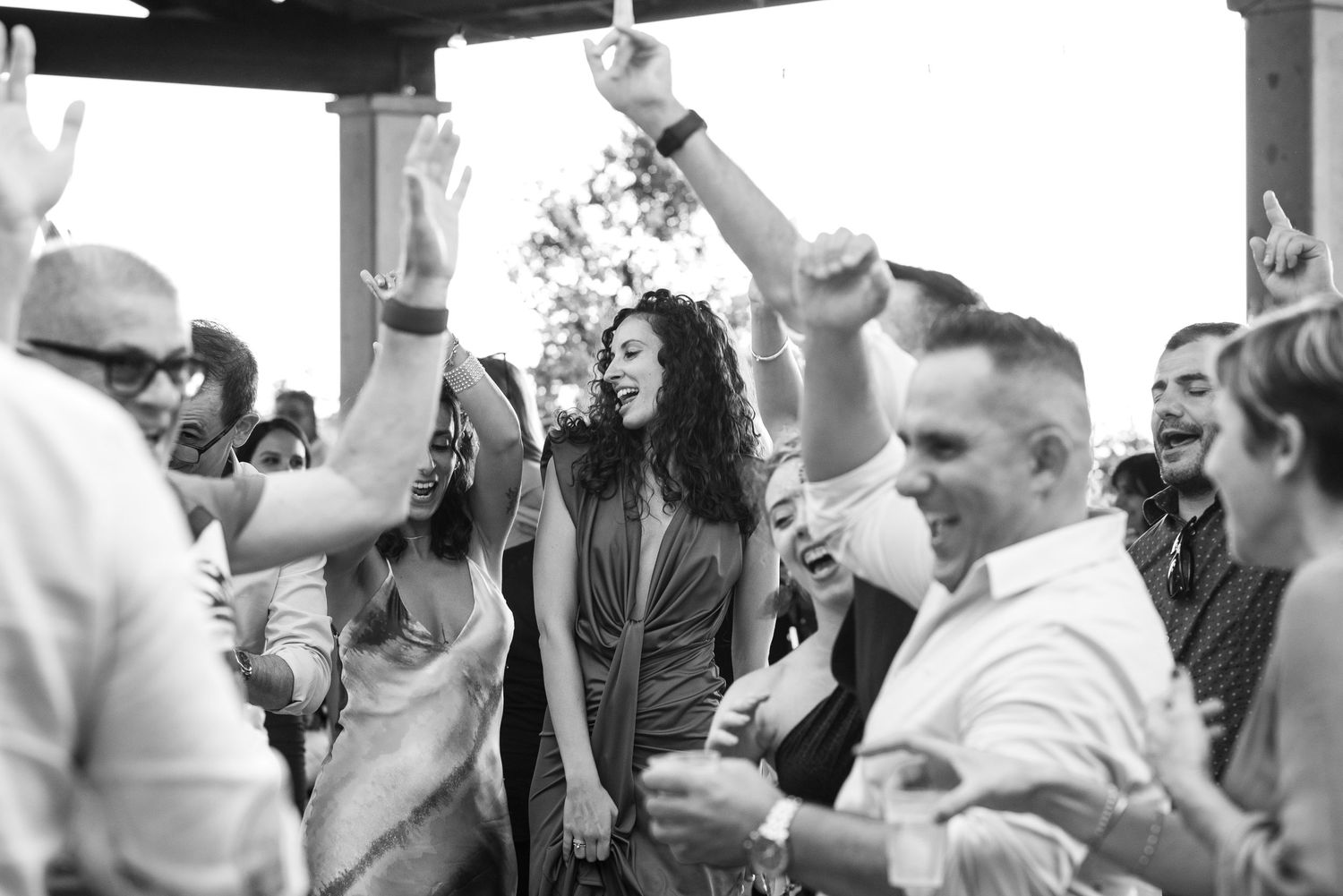 Wedding guests raising their drinks in celebration during an outdoor reception.