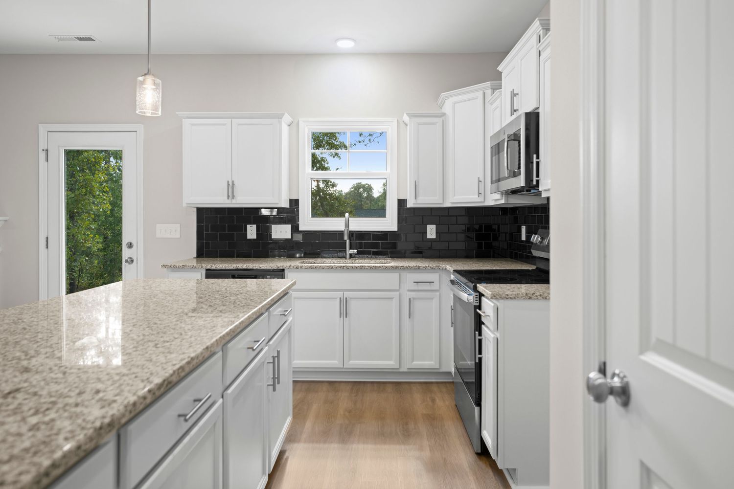 Contemporary kitchen with white cabinets, granite countertops, and stainless appliances in an L-shaped layout.