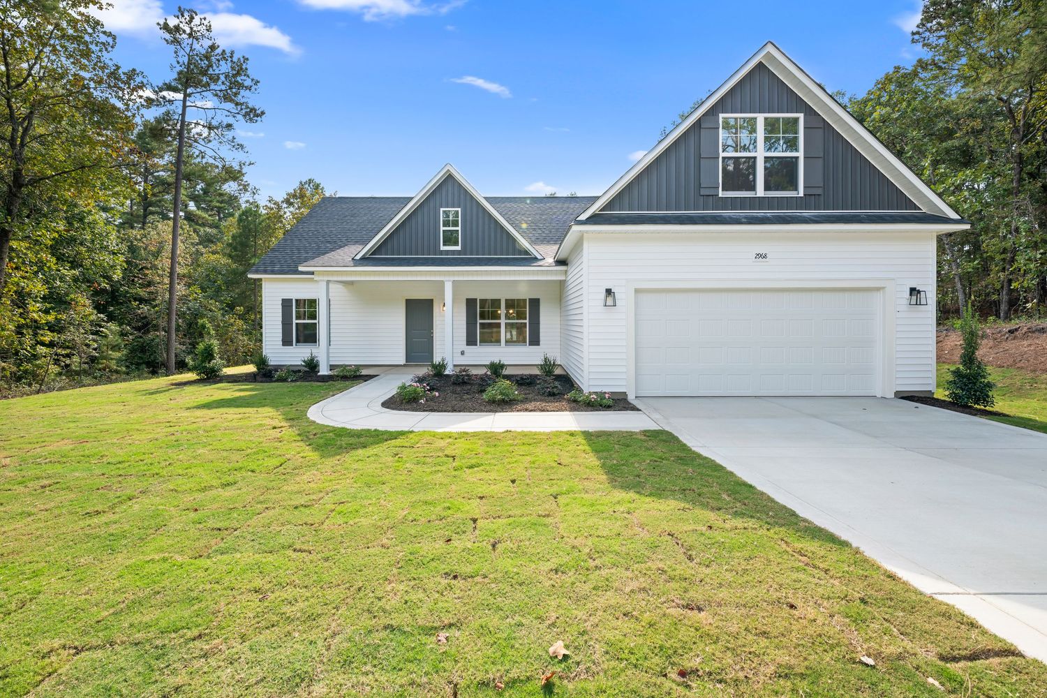 Modern farmhouse exterior with white siding, gray accents, and attached garage on a landscaped lot.