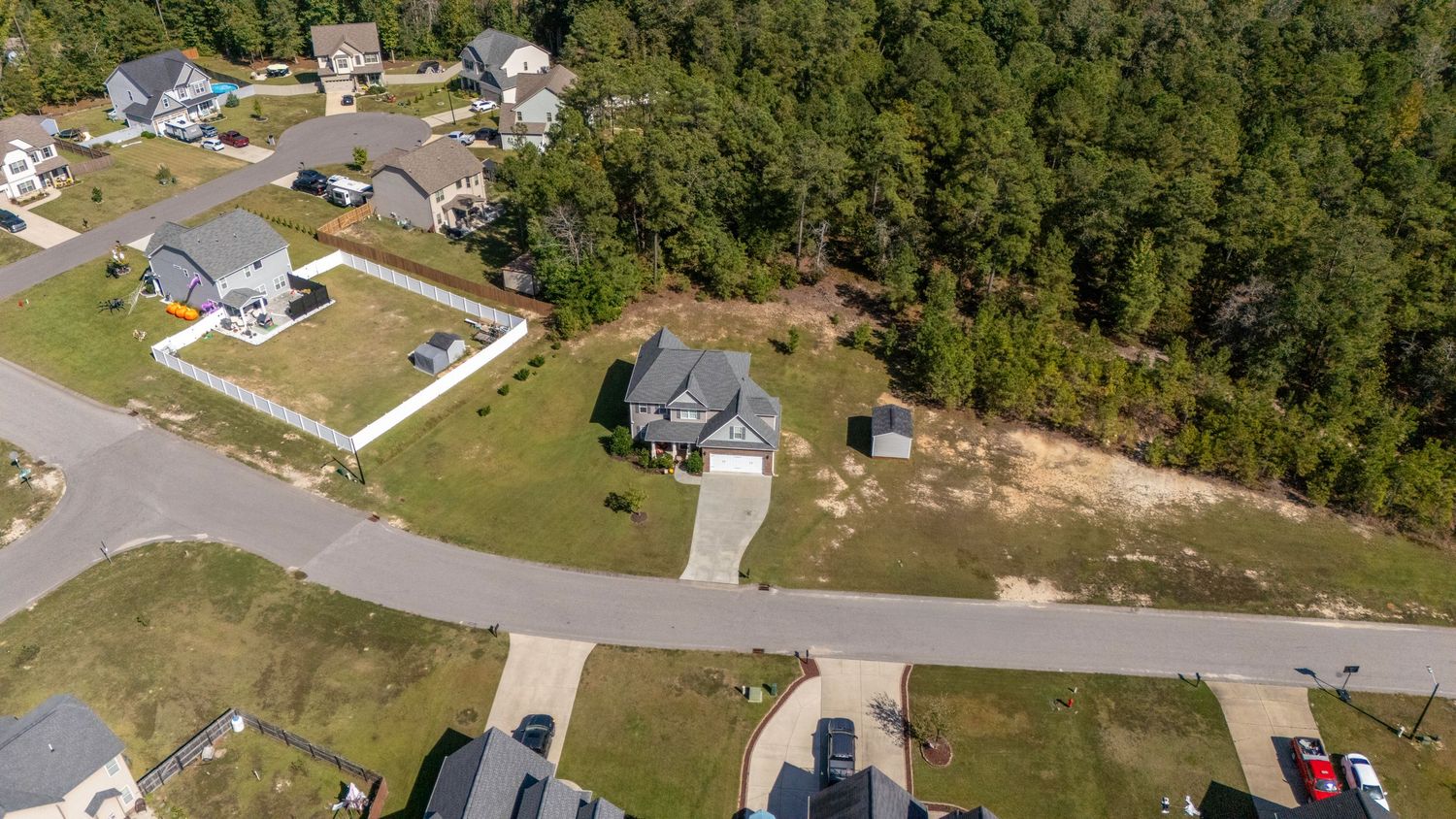 Drone shot of residential development with houses nestled among wooded areas.