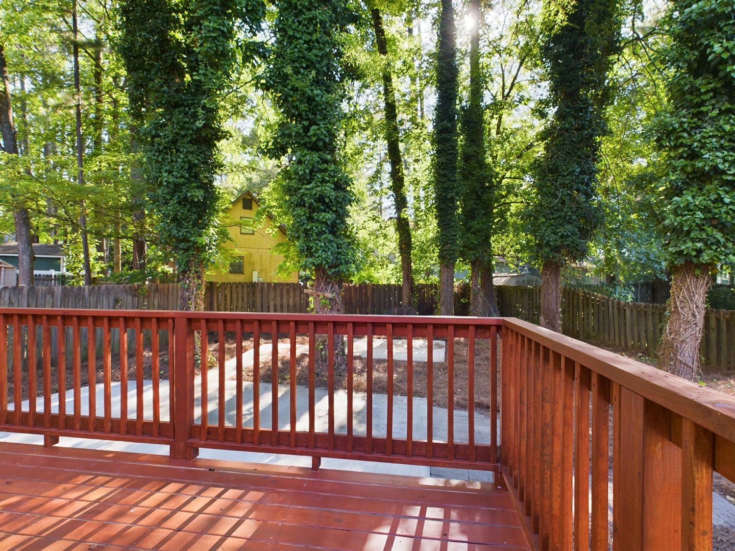 Wooden deck with railing surrounded by tall trees offering a serene outdoor living space.