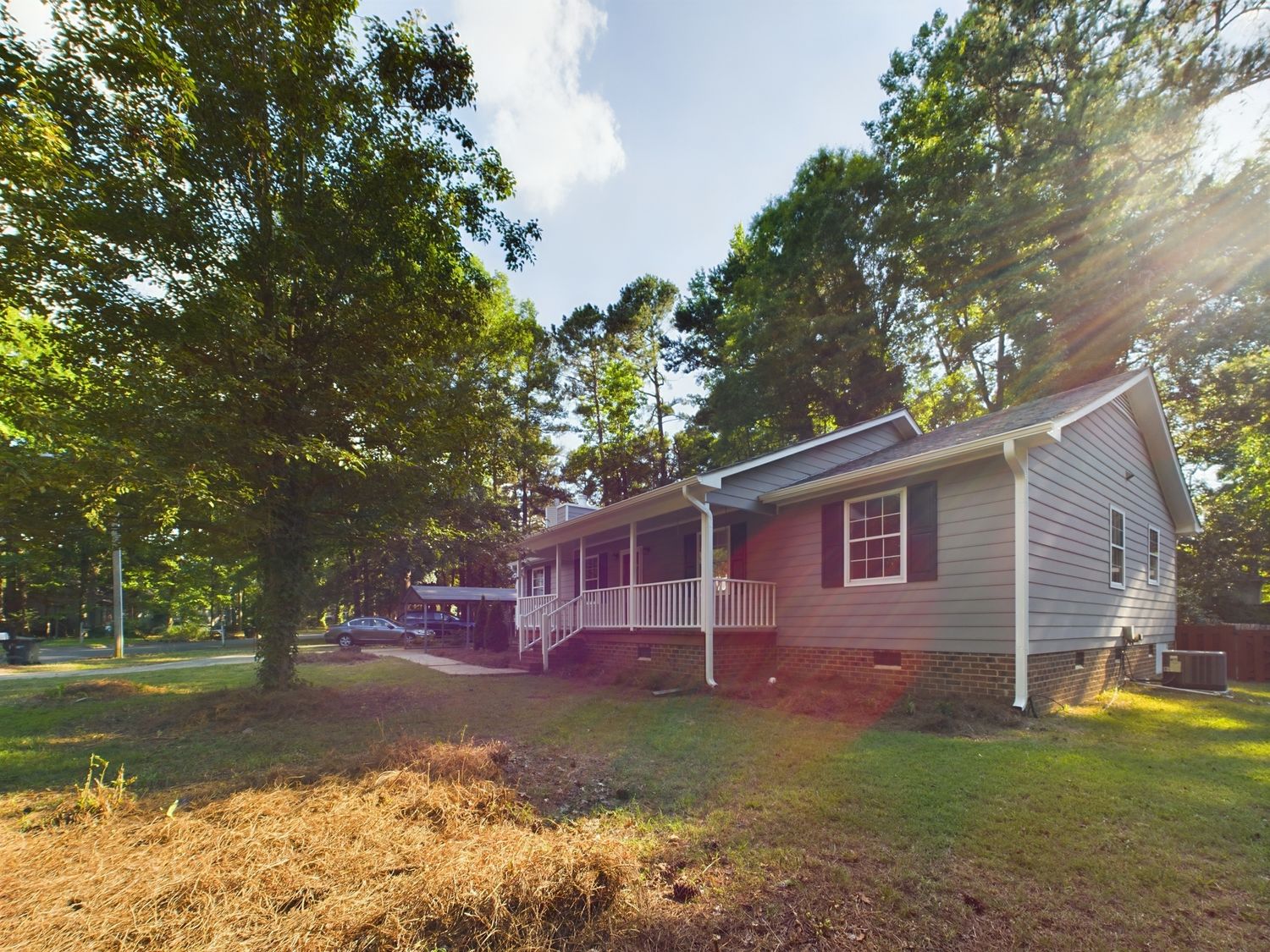 Exterior view of residential mobile homes and trailers in a park with trees and sunlight.