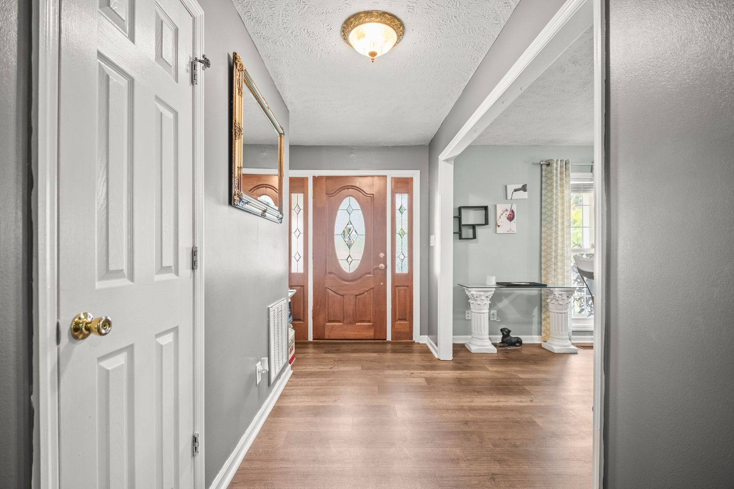Long hallway with white doors and walls featuring ceiling mounted light fixtures.