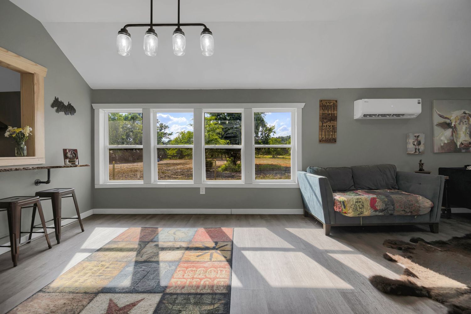 Bright living room with large windows, modern light fixture, and geometric area rug in neutral tones.