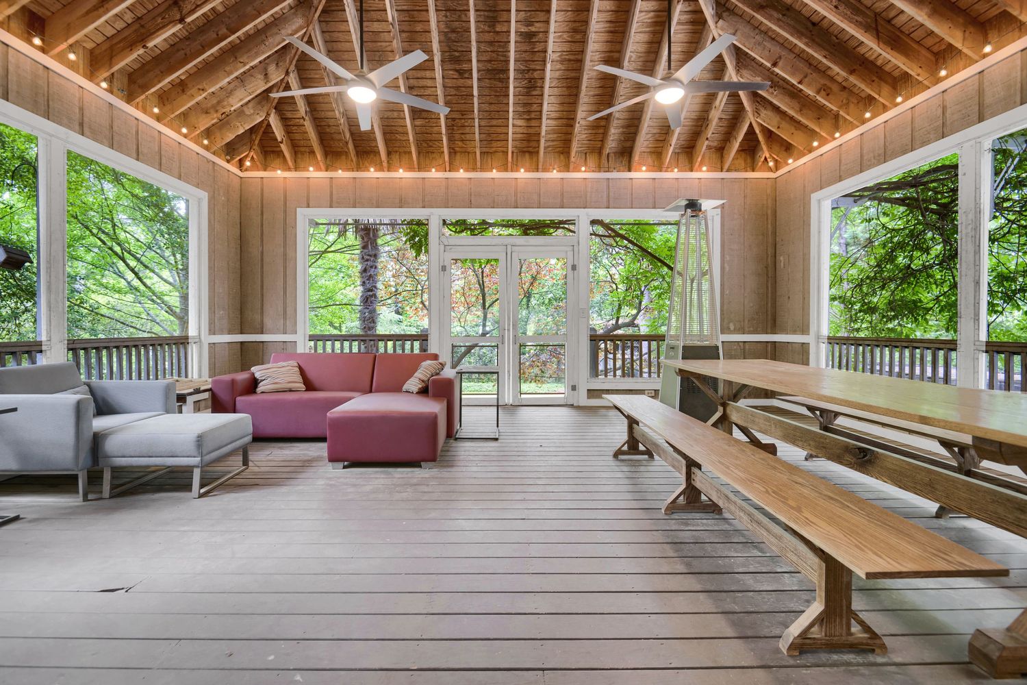 Rustic vaulted ceiling with exposed wooden beams and ceiling fans in a sunlit room.