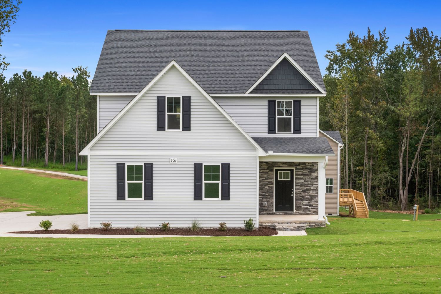 Collection of single-story ranch style homes with white siding and green lawns.