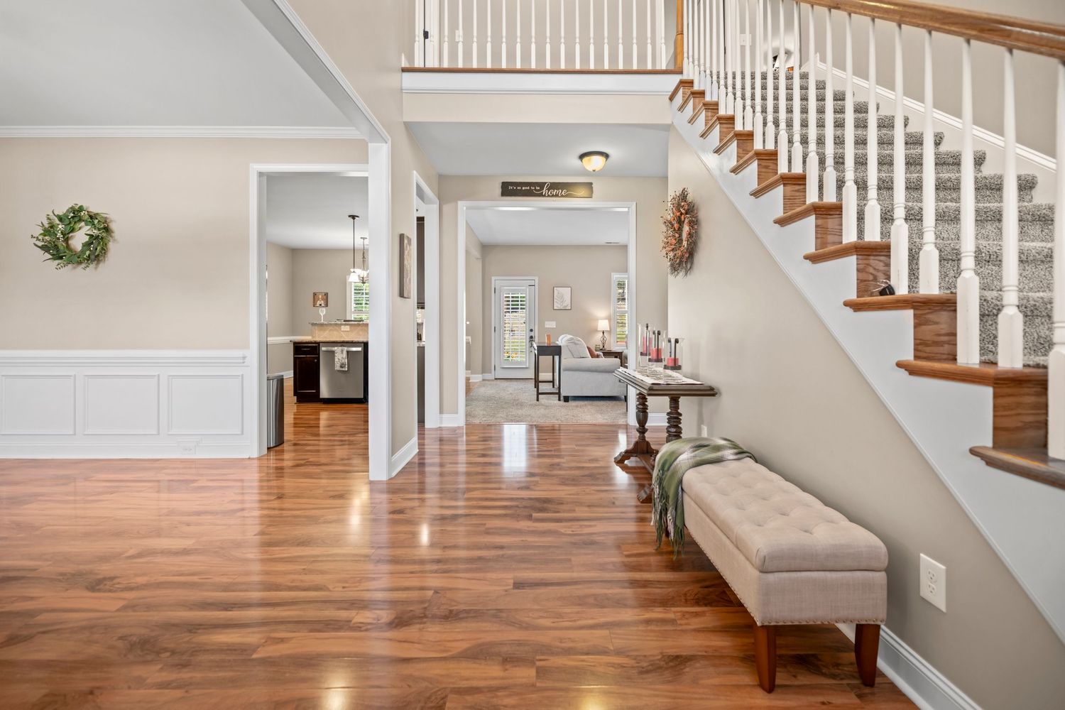 Open concept living space featuring hardwood floors, white trim, and traditional staircase.