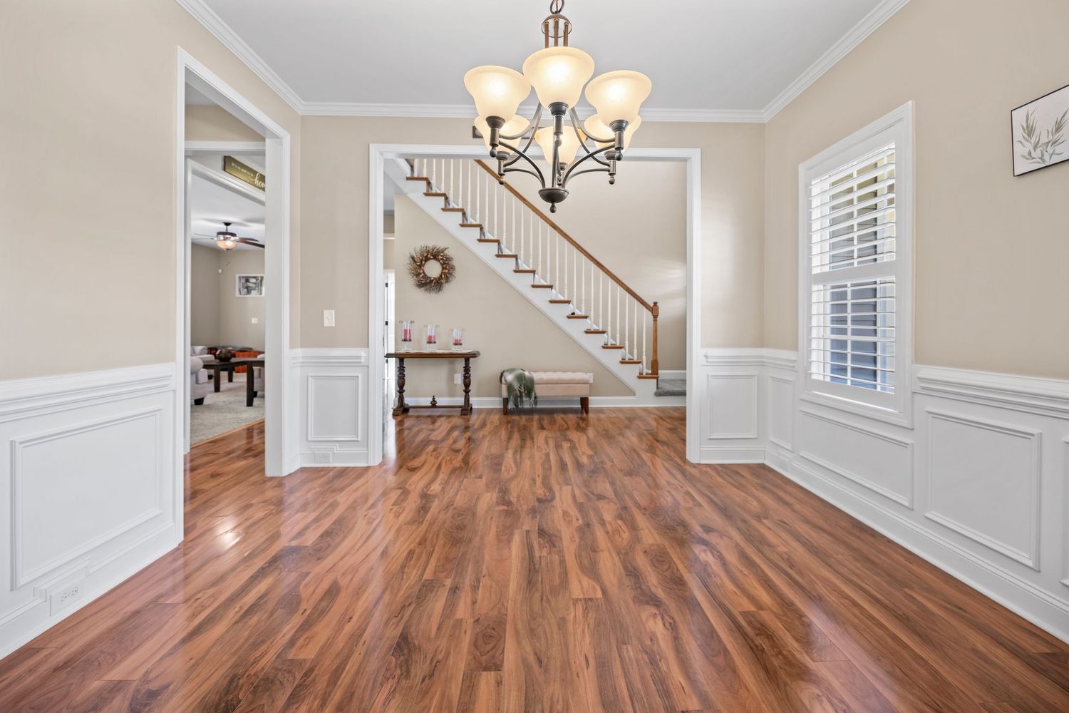 Elegant living room interior with crown molding, chandelier, and wainscoting details.