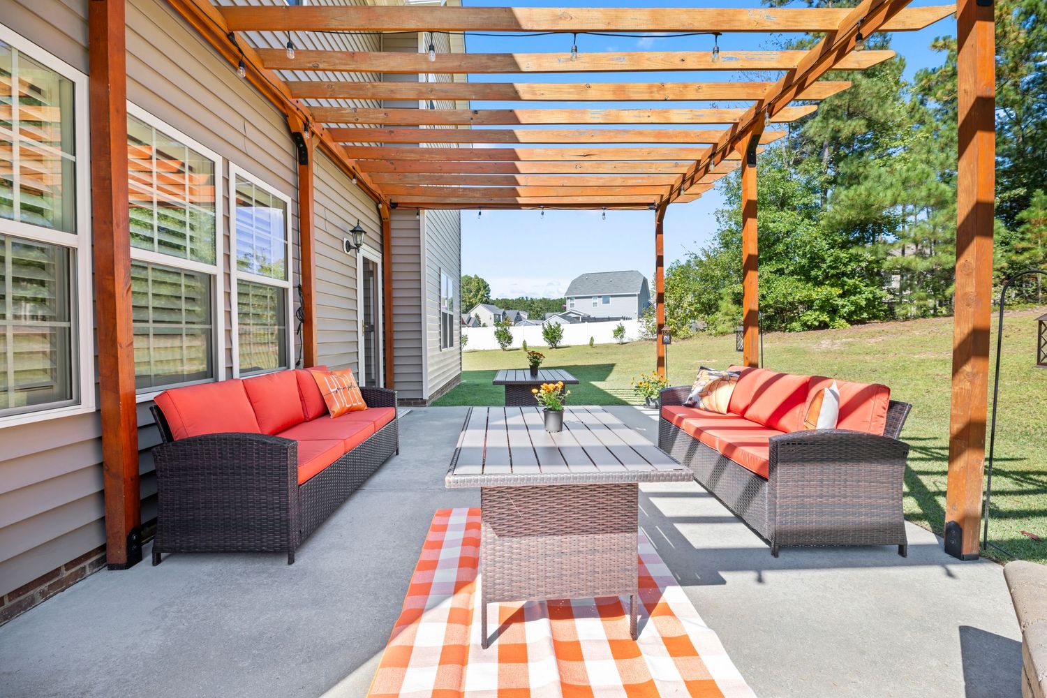 Covered patio with pergola and red cushioned outdoor seating area.