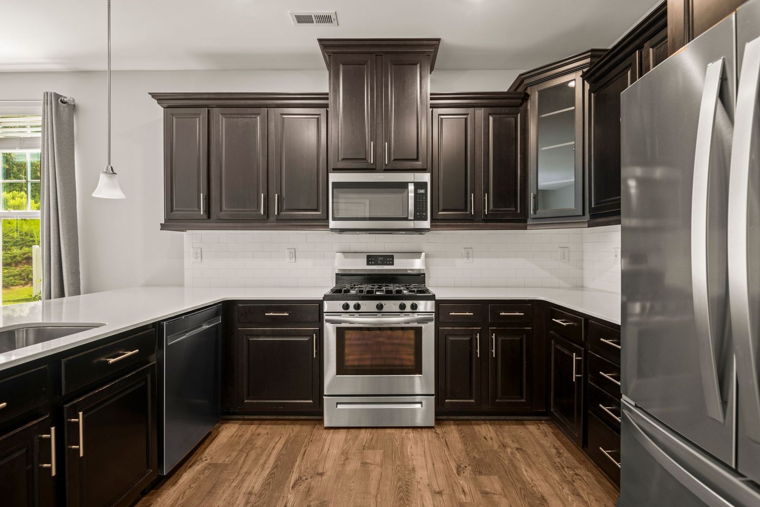 Modern kitchen with dark wood cabinets, stainless steel appliances, and granite countertops in an open layout design.