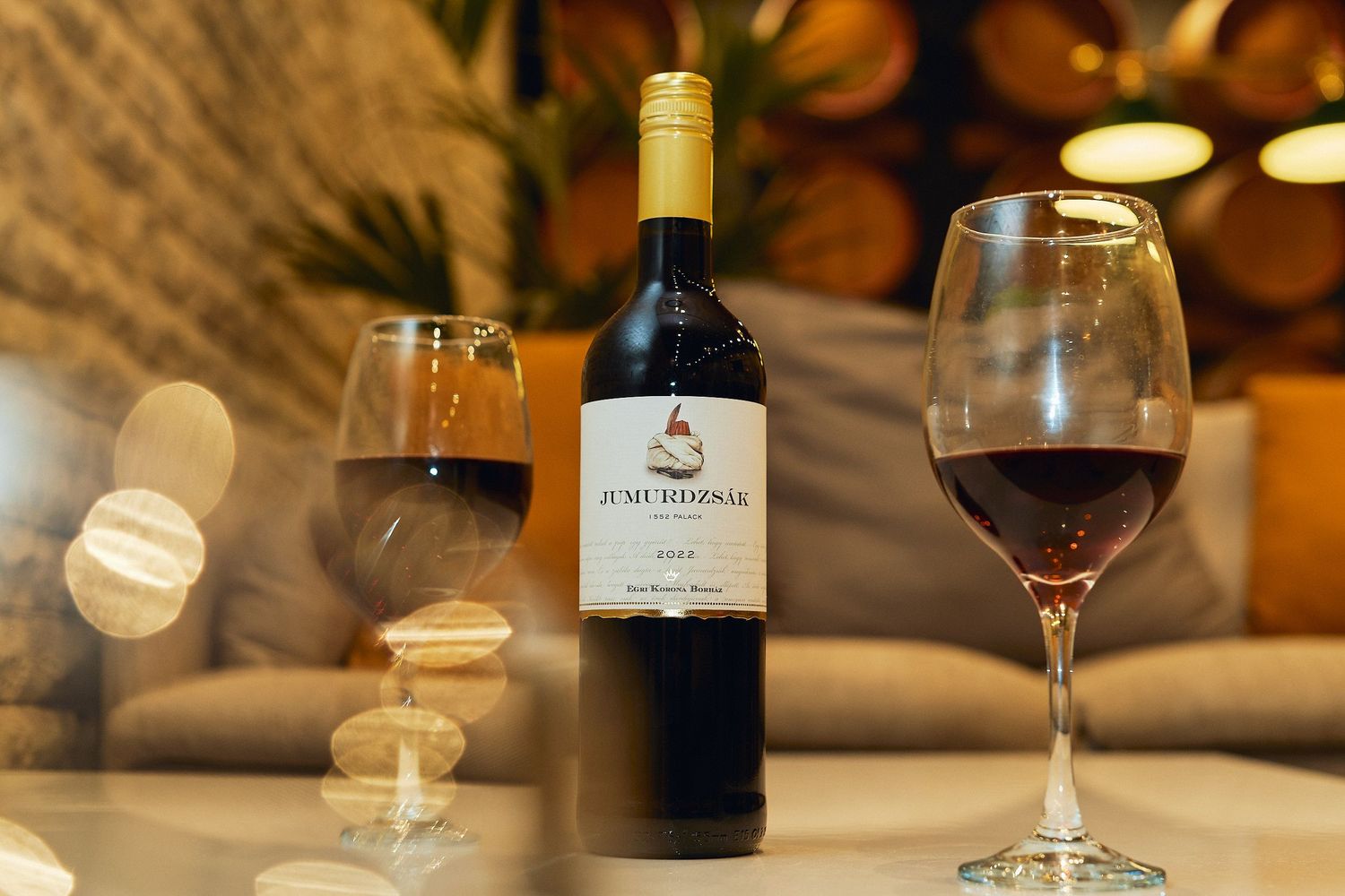 Wine bottles and glasses arranged on a wooden table in a cozy restaurant setting with warm ambient lighting.