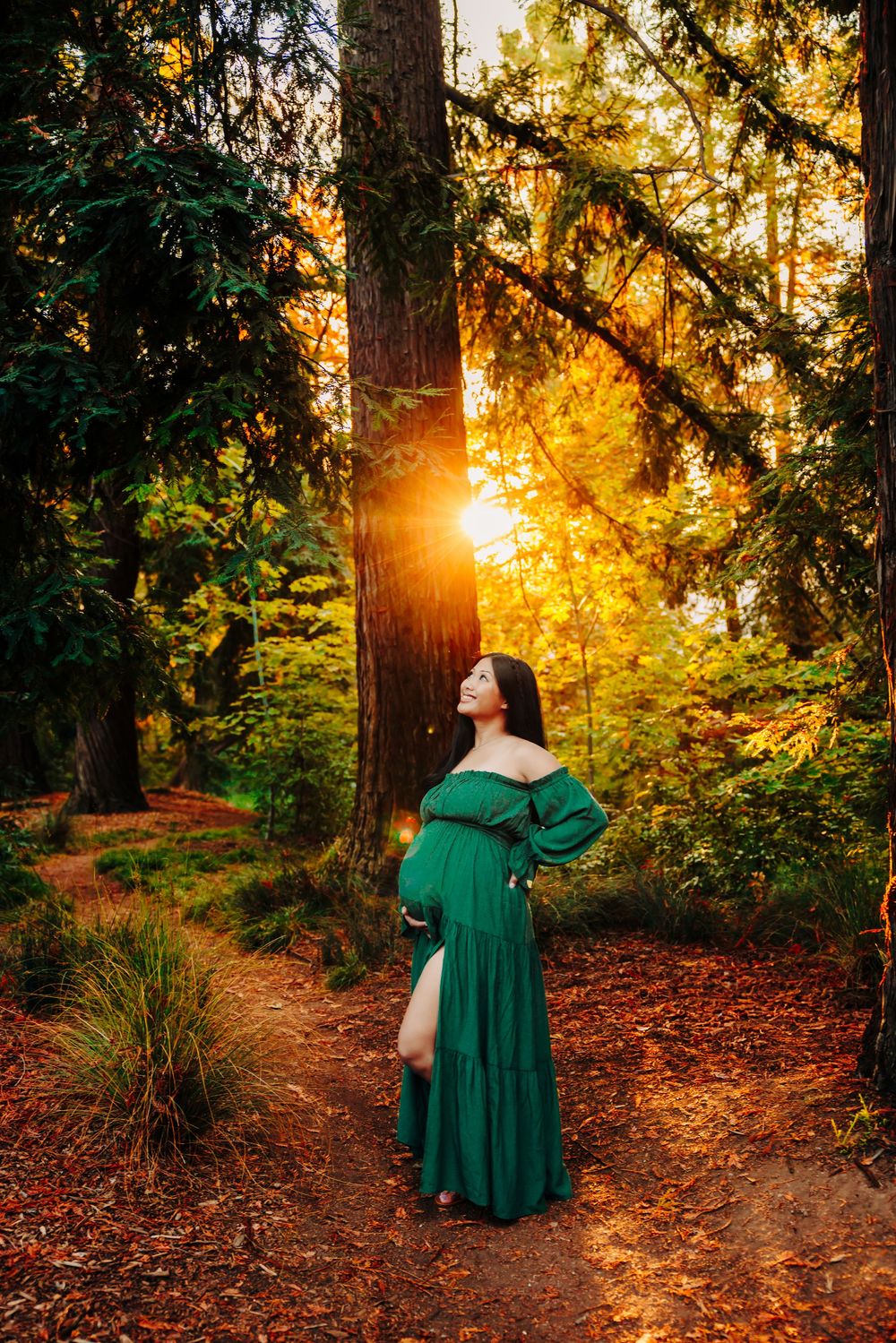 Emerald green dress contrasts beautifully with autumn forest colors at sunset.